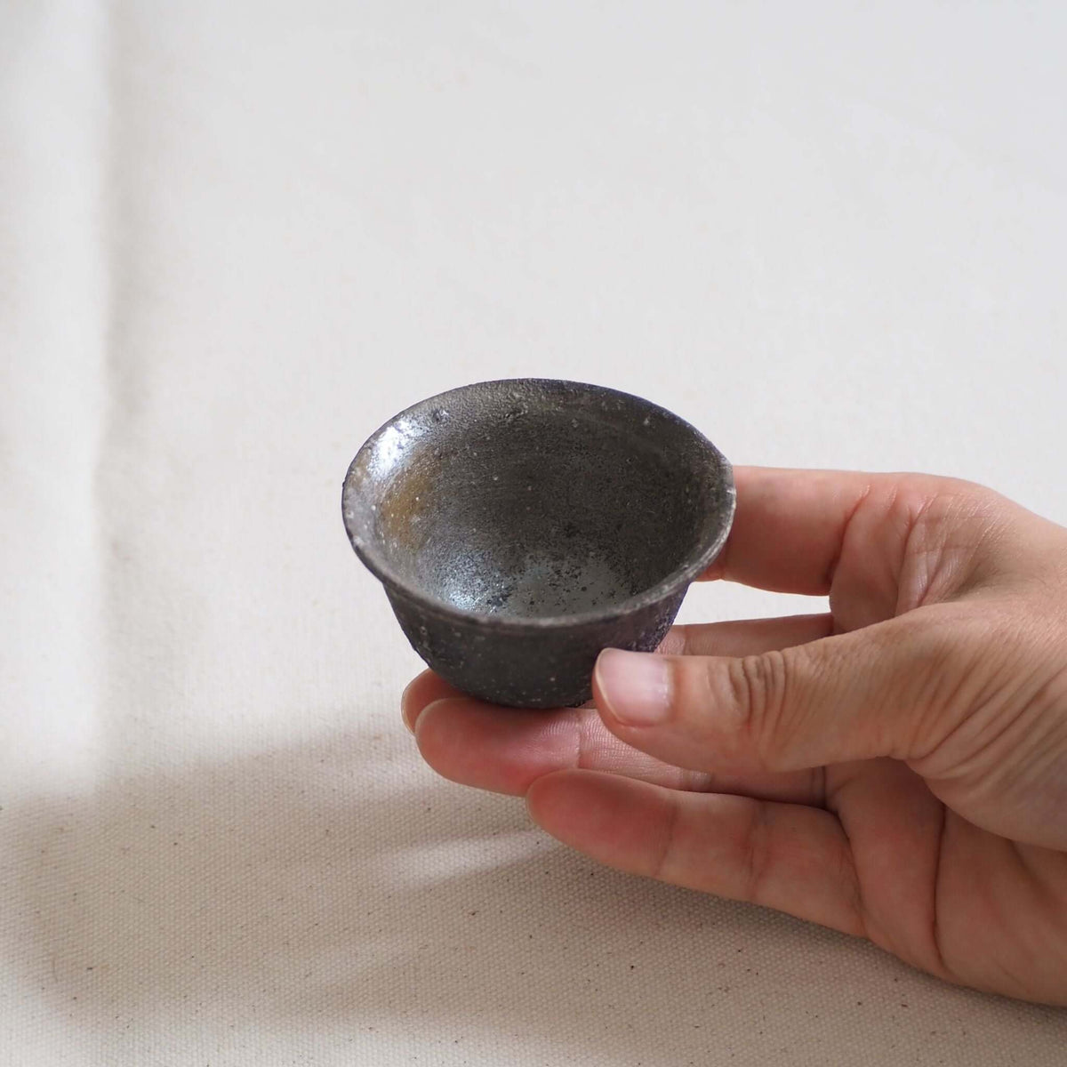 備前焼灰窯変茶杯を手で持っている