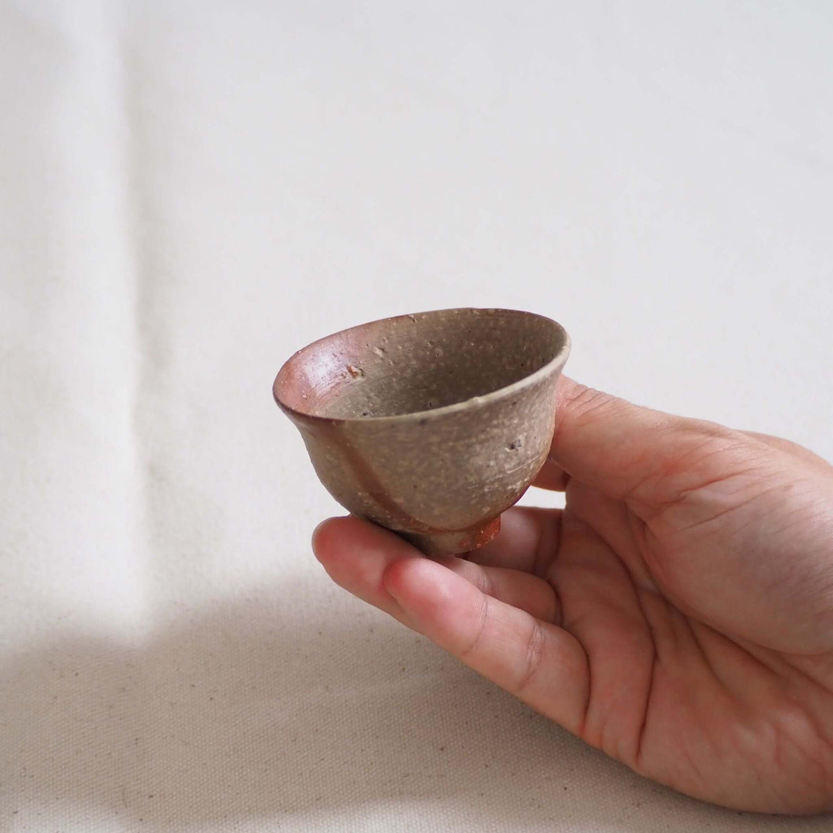 備前焼緋襷茶杯を手で持っている