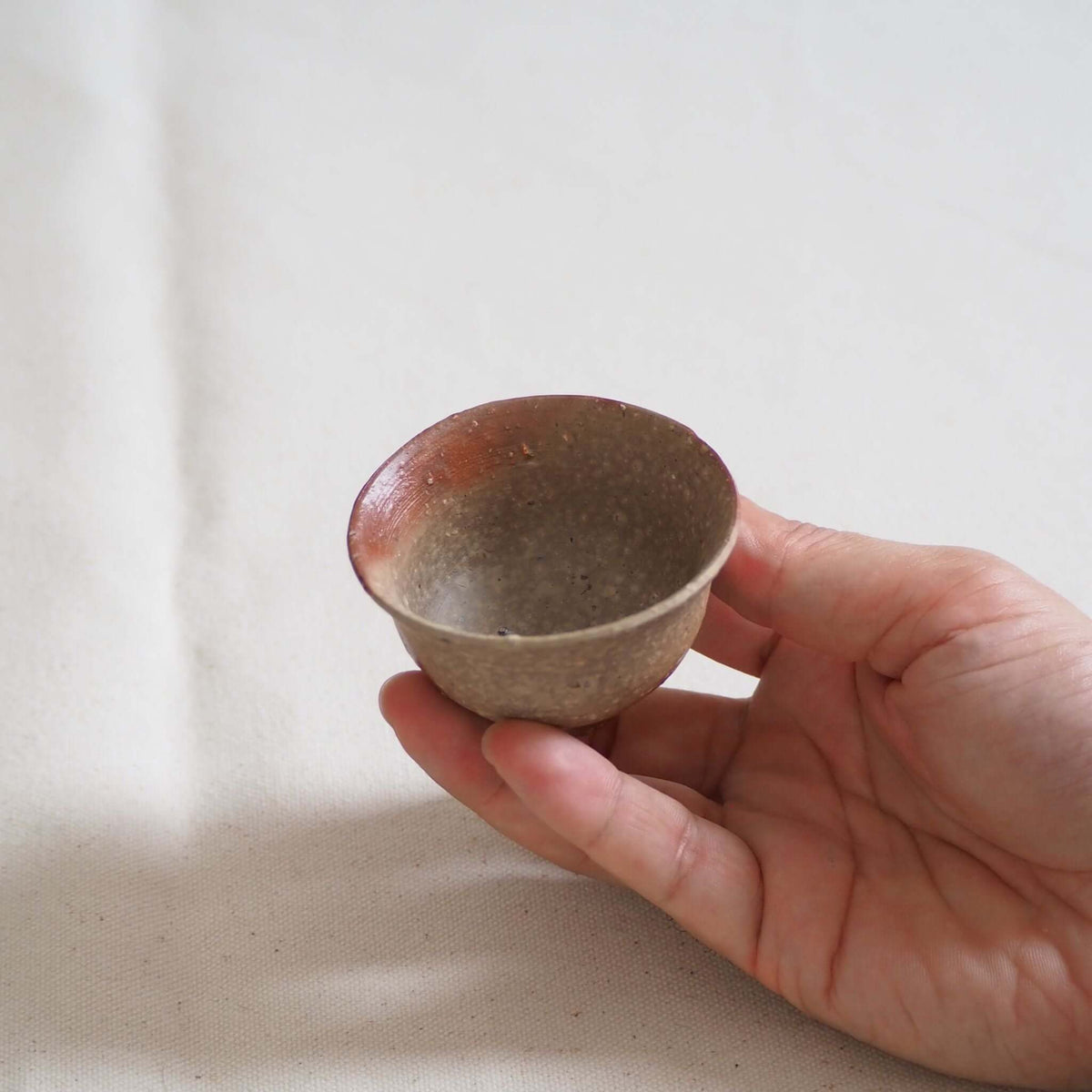 備前焼緋襷茶杯を手で持っている