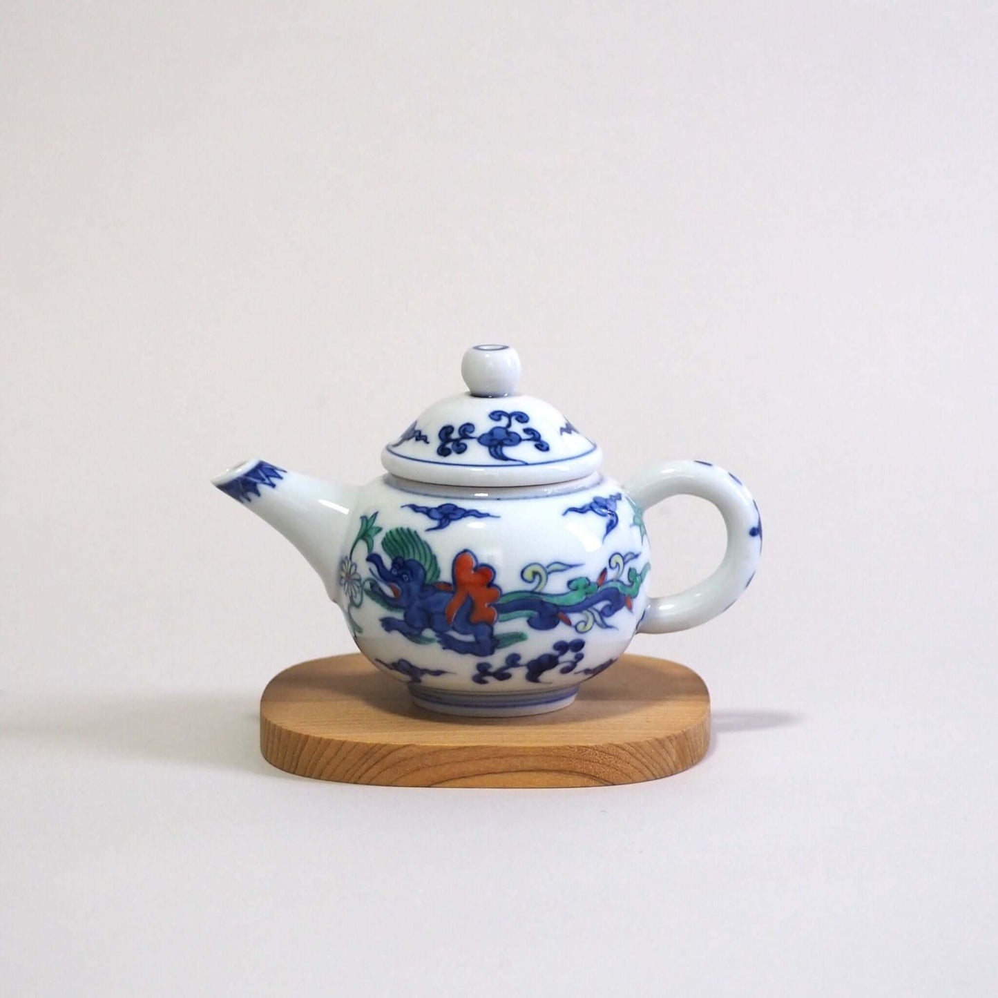 A Kyo-yaki teapot with a colorful dragon design by Shoami, seen from the side. The spout is on the left and the handle is on the right.