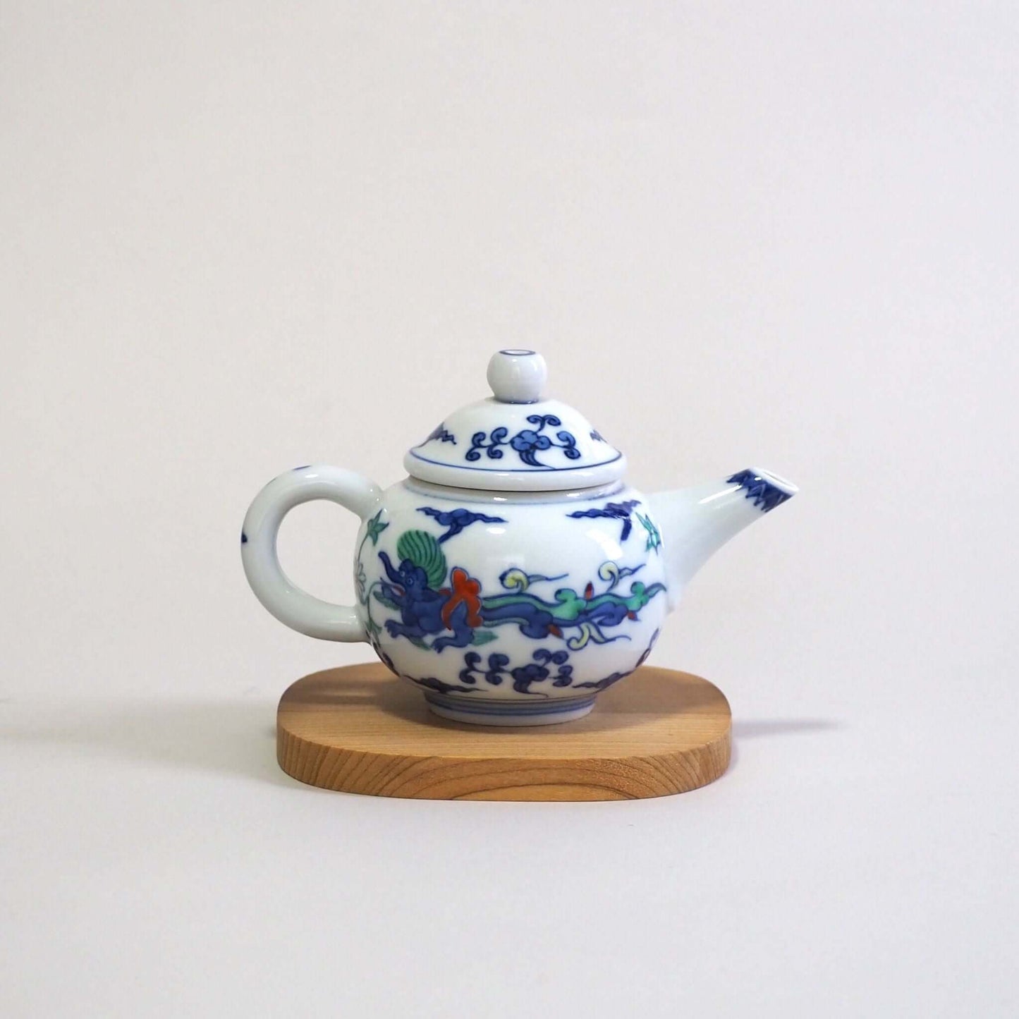 A Kyo-yaki teapot with a colorful dragon design by Shoami, seen from the side. The spout is on the left and the handle is on the right.