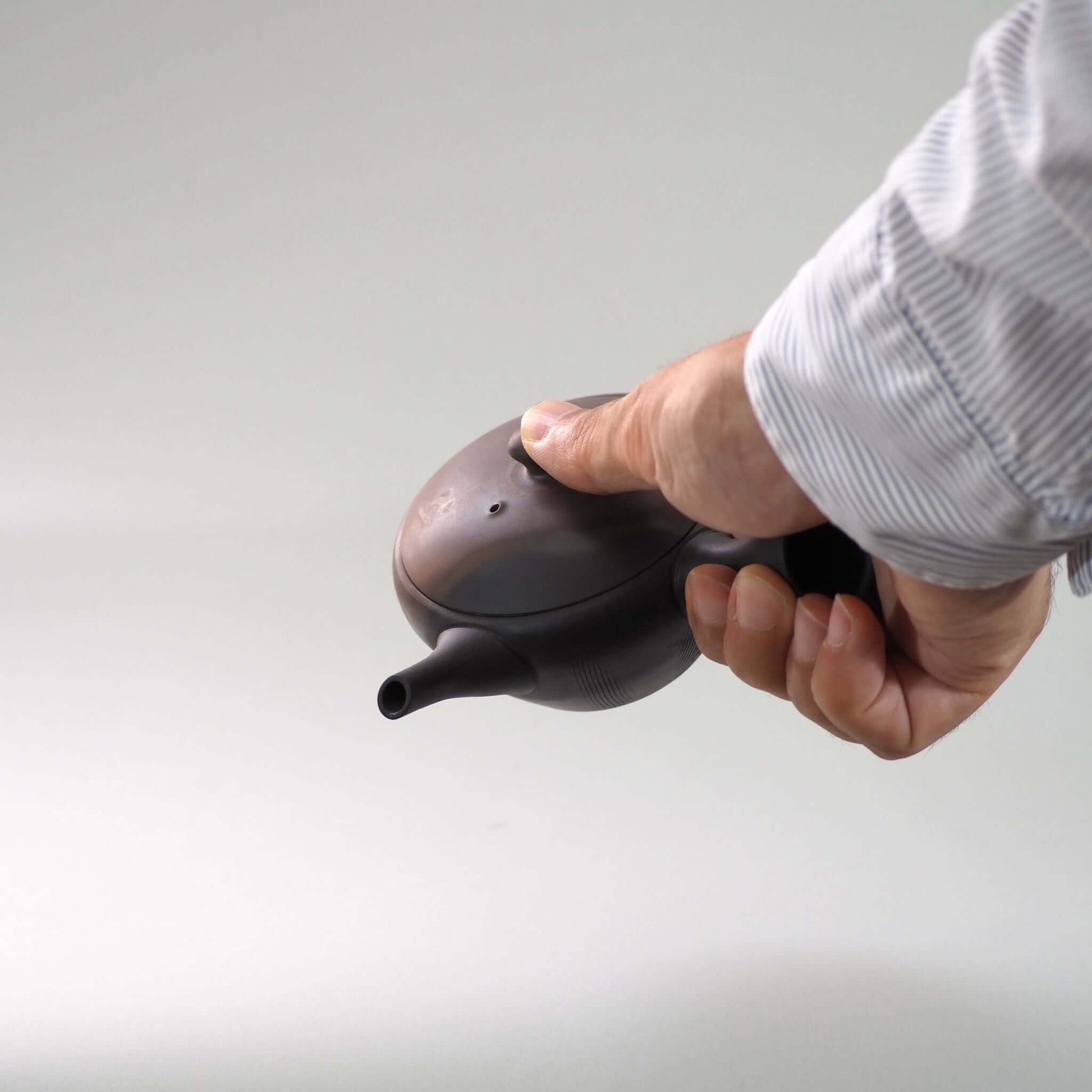 常滑焼玉光陶園の窯変平丸急須を手で持ち、傾けている