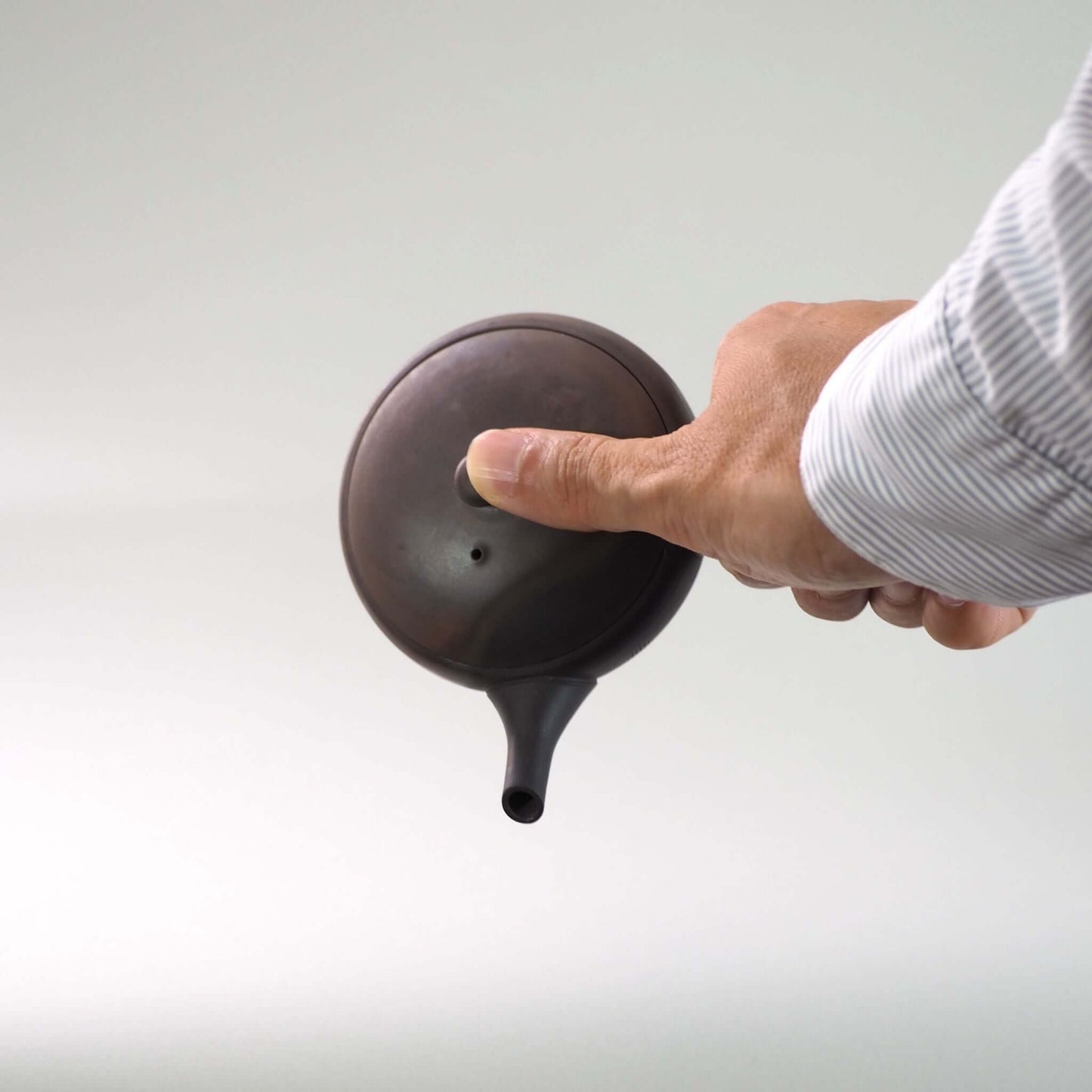 常滑焼玉光陶園の窯変平丸急須を手で持ち、注ぐ様子。