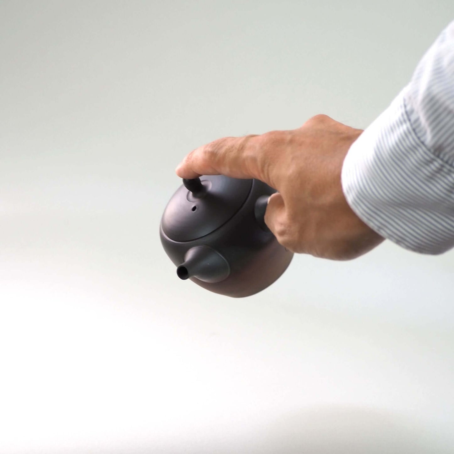 常滑焼玉光陶園の窯変長丸急須の蓋を押さえながら手で持っている