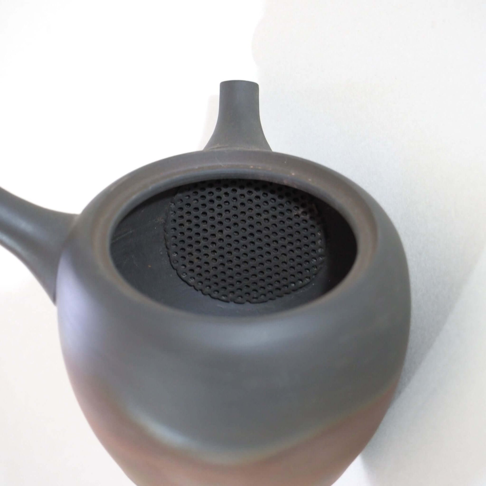 常滑焼玉光陶園の窯変長丸急須の蓋を開け、内側の茶漉しを見ている