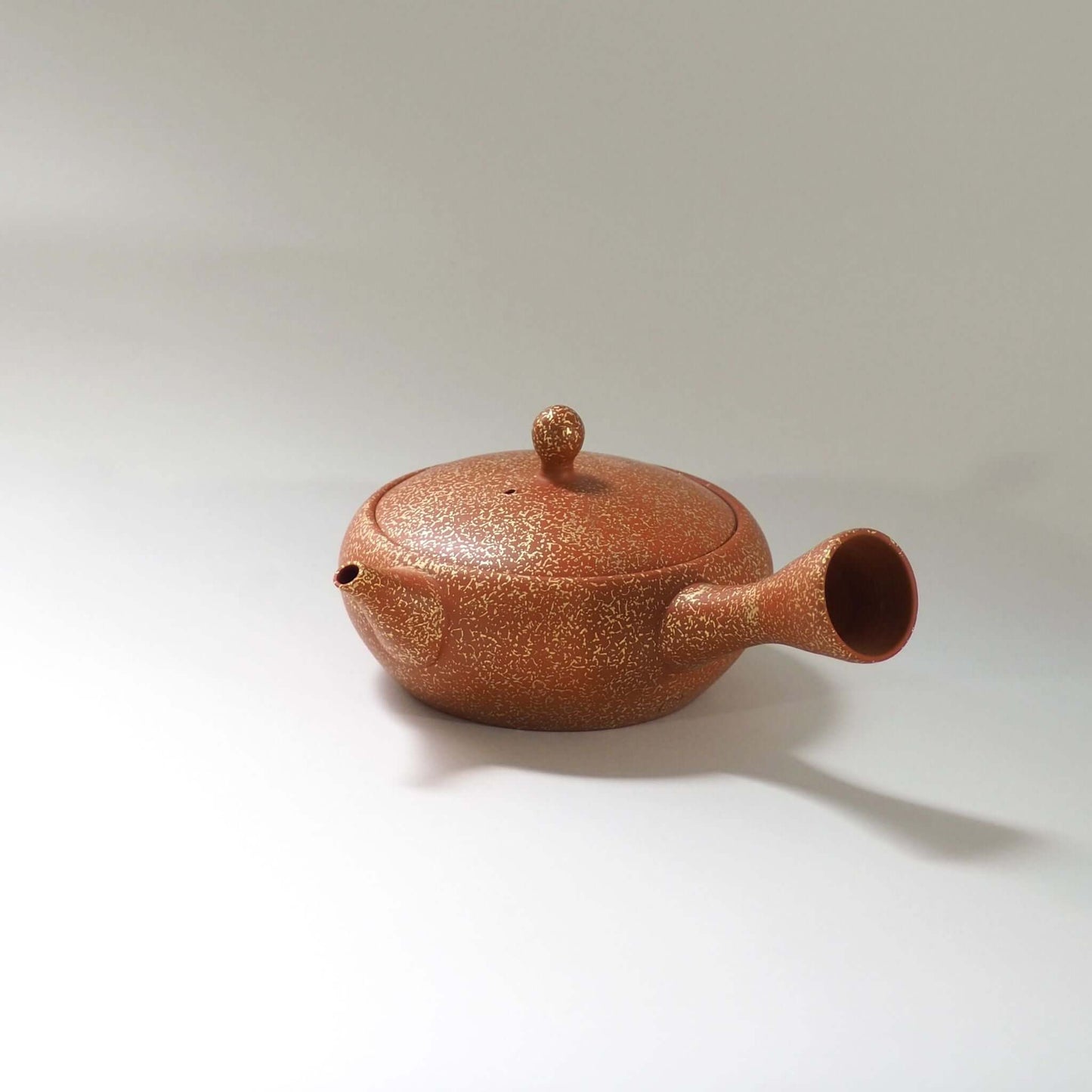 常滑焼玉光陶園の朱泥平丸金たたき急須を正面から見ている。注ぎ口が左、把手が右にある
