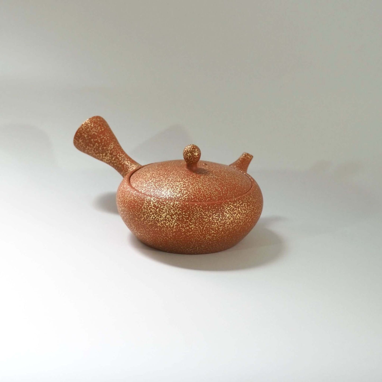 常滑焼玉光陶園の朱泥平丸金たたき急須を正面から見ている。注ぎ口が右、把手が左にある
