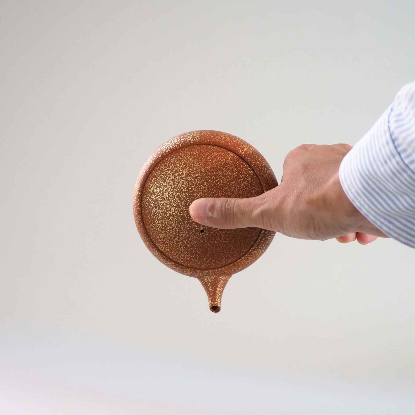 常滑焼玉光陶園の朱泥平丸金たたき急須の蓋を押さえ、注ぐ様子