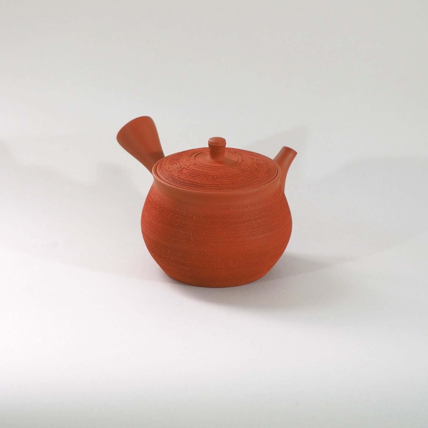 常滑焼玉光陶園の朱泥松皮急須を正面から見ている。注ぎ口が右、把手が左にある
