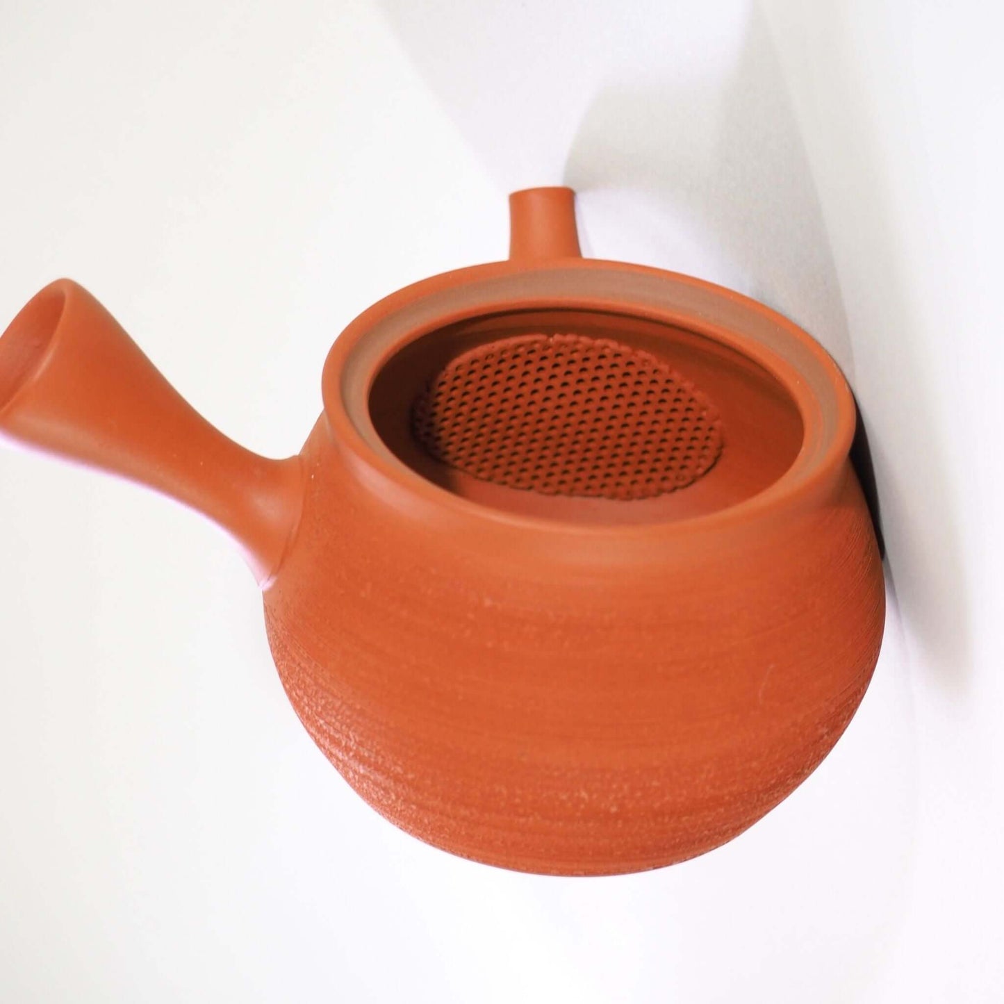 常滑焼玉光陶園の朱泥松皮急須の蓋を開け、内側の茶漉しを見ている