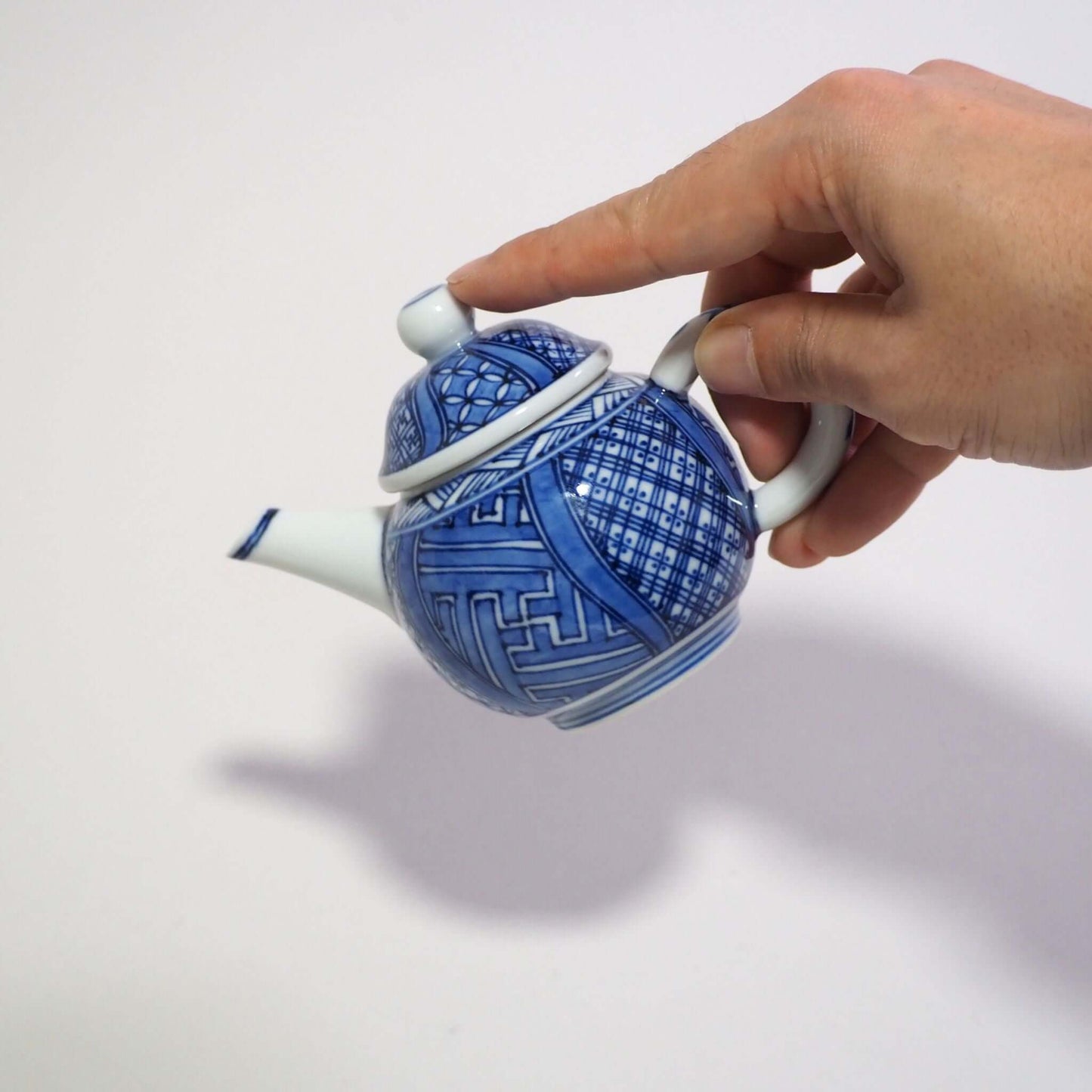 Holding a Kyoyaki Shoami sometsuke Shōzui teapot by hand.