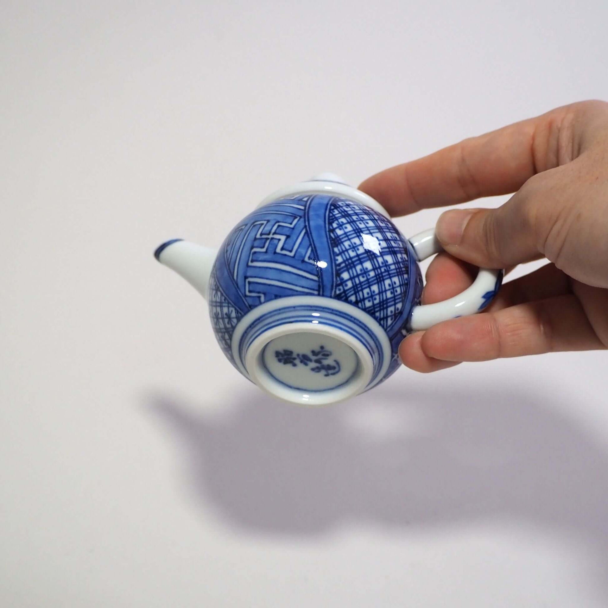 Holding a Kyo-yaki Shōami blue-and-white Shōzui teapot by hand, looking at the bottom area.