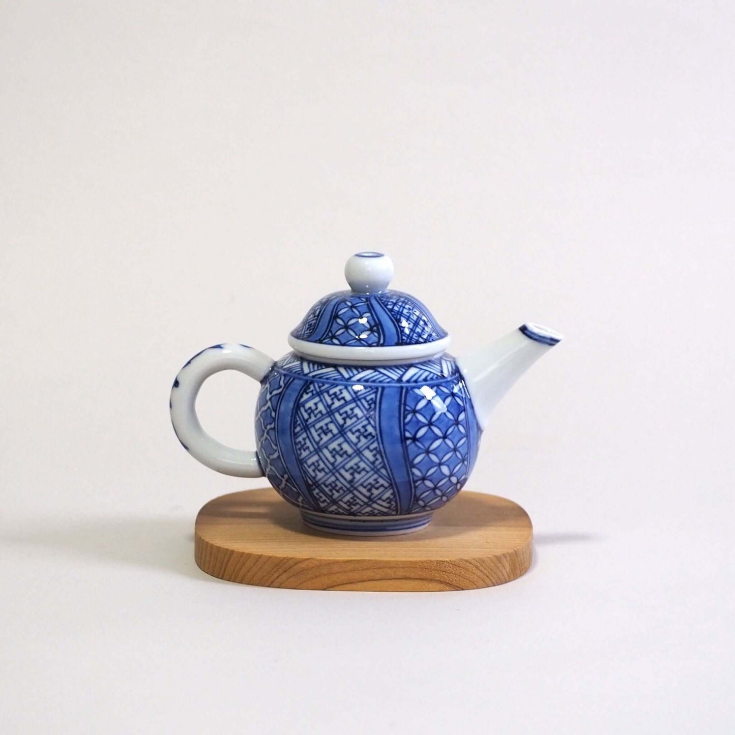 A Kyoyaki Shoami dyed Shozui teapot is viewed from the side. The spout is on the right and the handle is on the left.