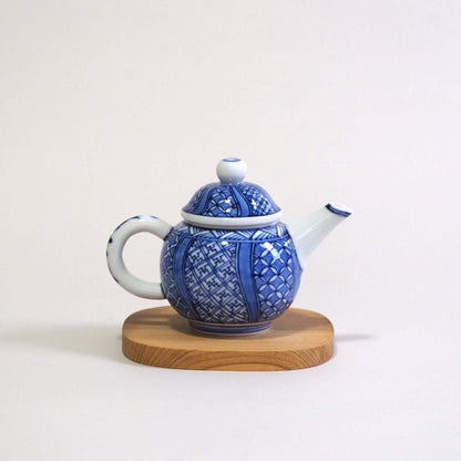 A Kyoyaki Shoami dyed Shozui teapot is viewed from the side. The spout is on the right and the handle is on the left.