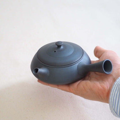 Holding by hand a black triangular ultra-flat teapot by Tokoname ceramic artist Tokuta Fujita