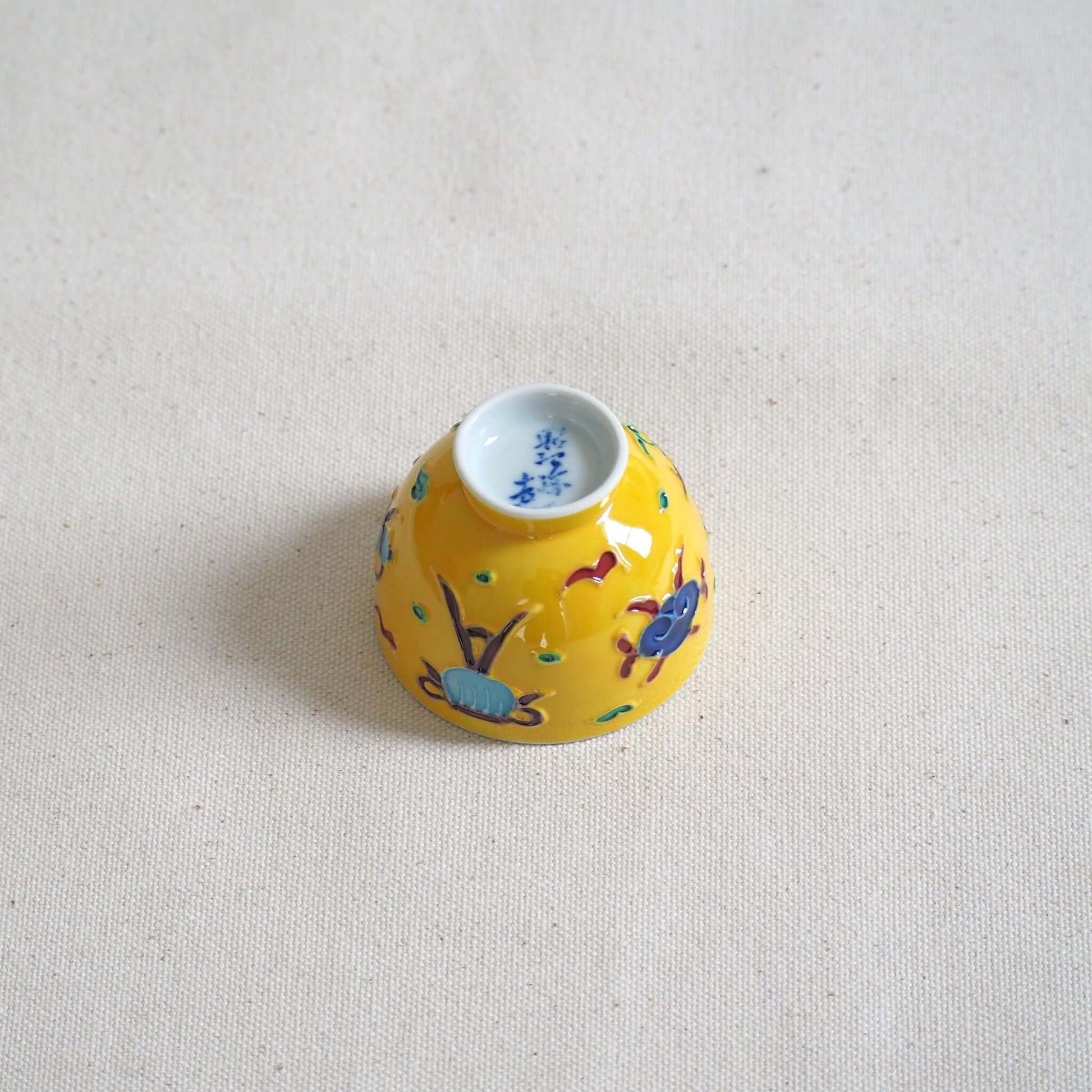 京焼 昭阿弥作 黄交趾鳳凰茶杯 交趾焼 鳳凰文様 伝統工芸 京都陶器　裏返して底を見ている