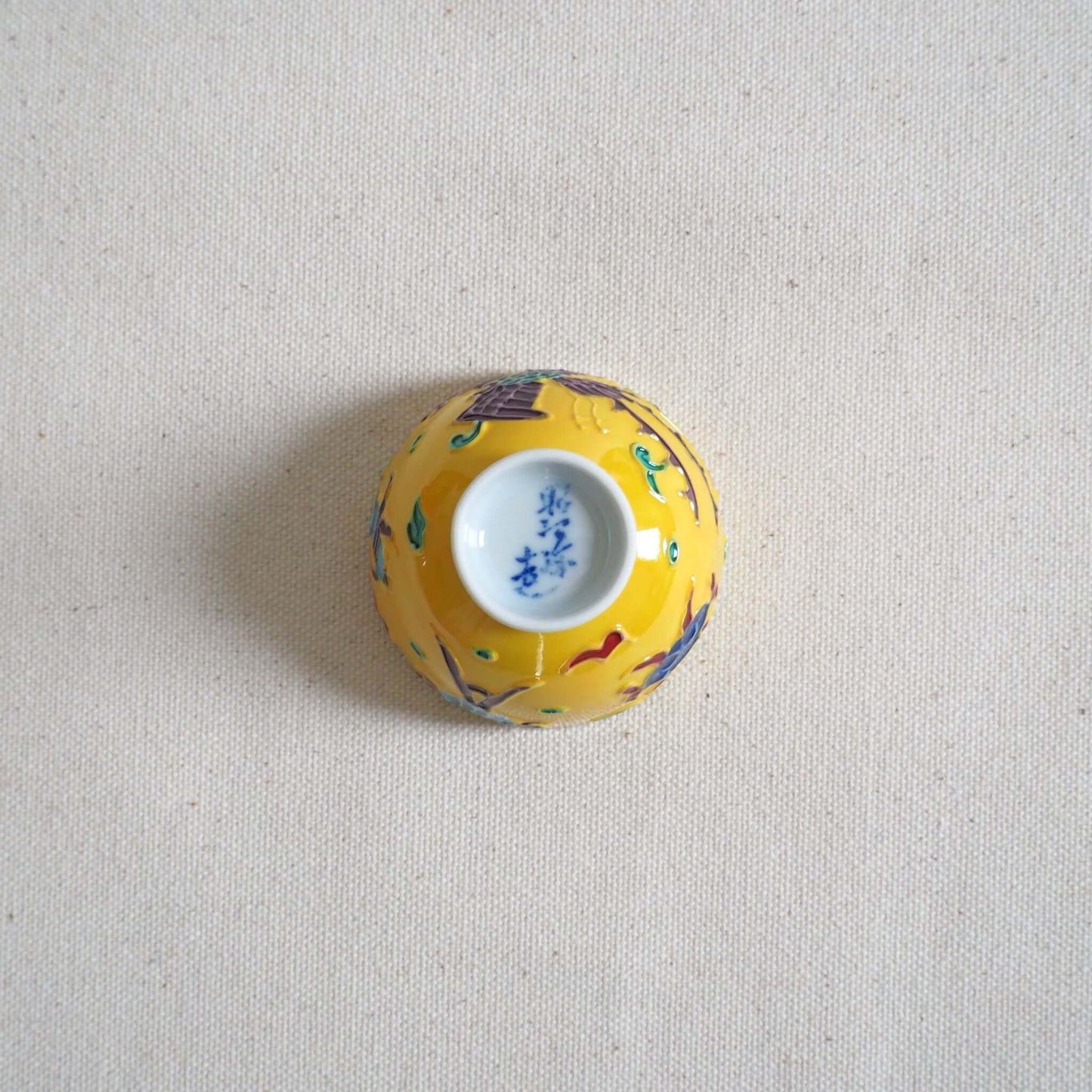 京焼 昭阿弥作 黄交趾鳳凰茶杯 交趾焼 鳳凰文様 伝統工芸 京都陶器　裏返して底を見ている