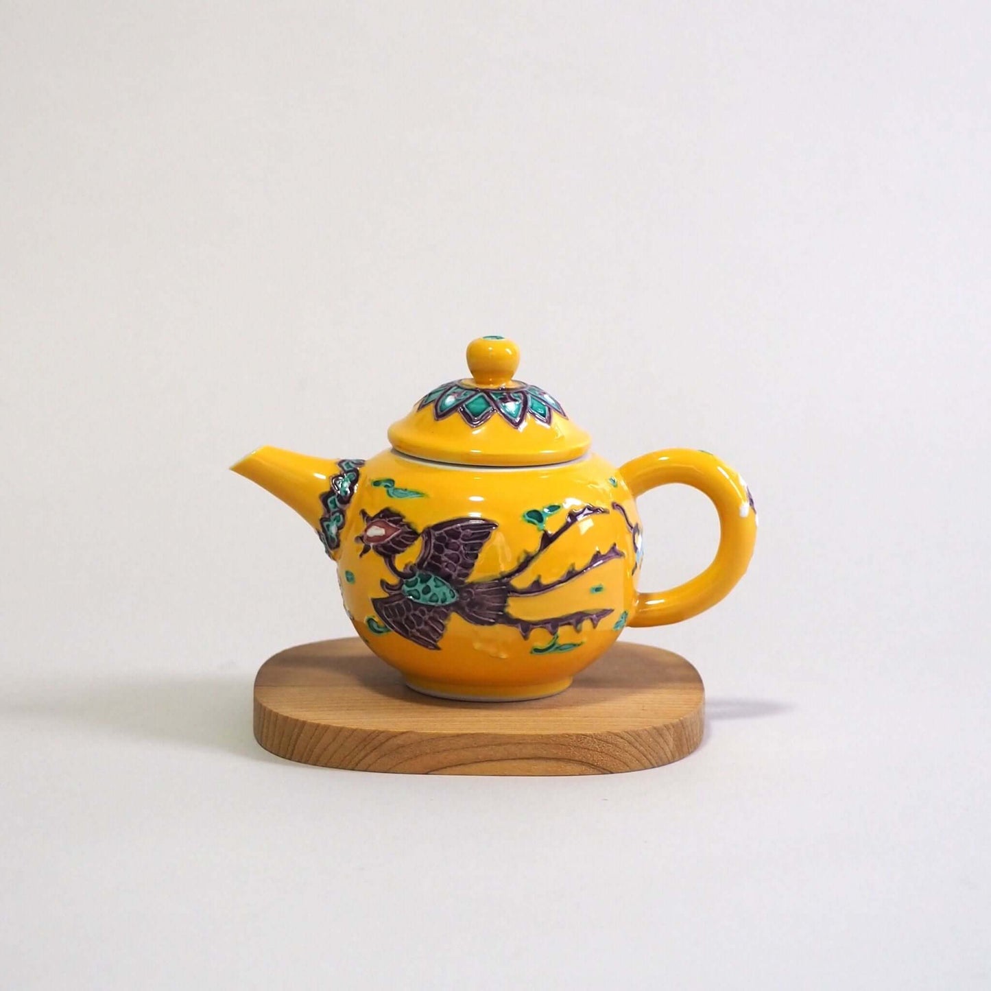 Looking at a Kyo-yaki Aomi yellow-glazed phoenix teapot from the side. The spout is on the left, and the handle is on the right.