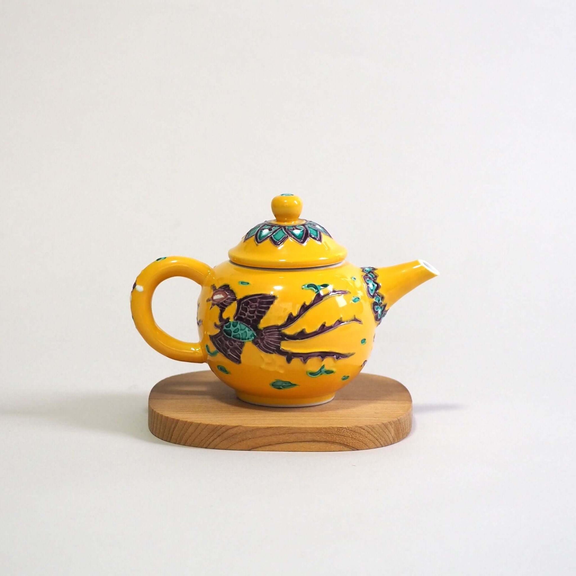 Looking at a Kyo-yaki Aomi yellow-glazed phoenix teapot from the side. The spout is on the right, and the handle is on the left.