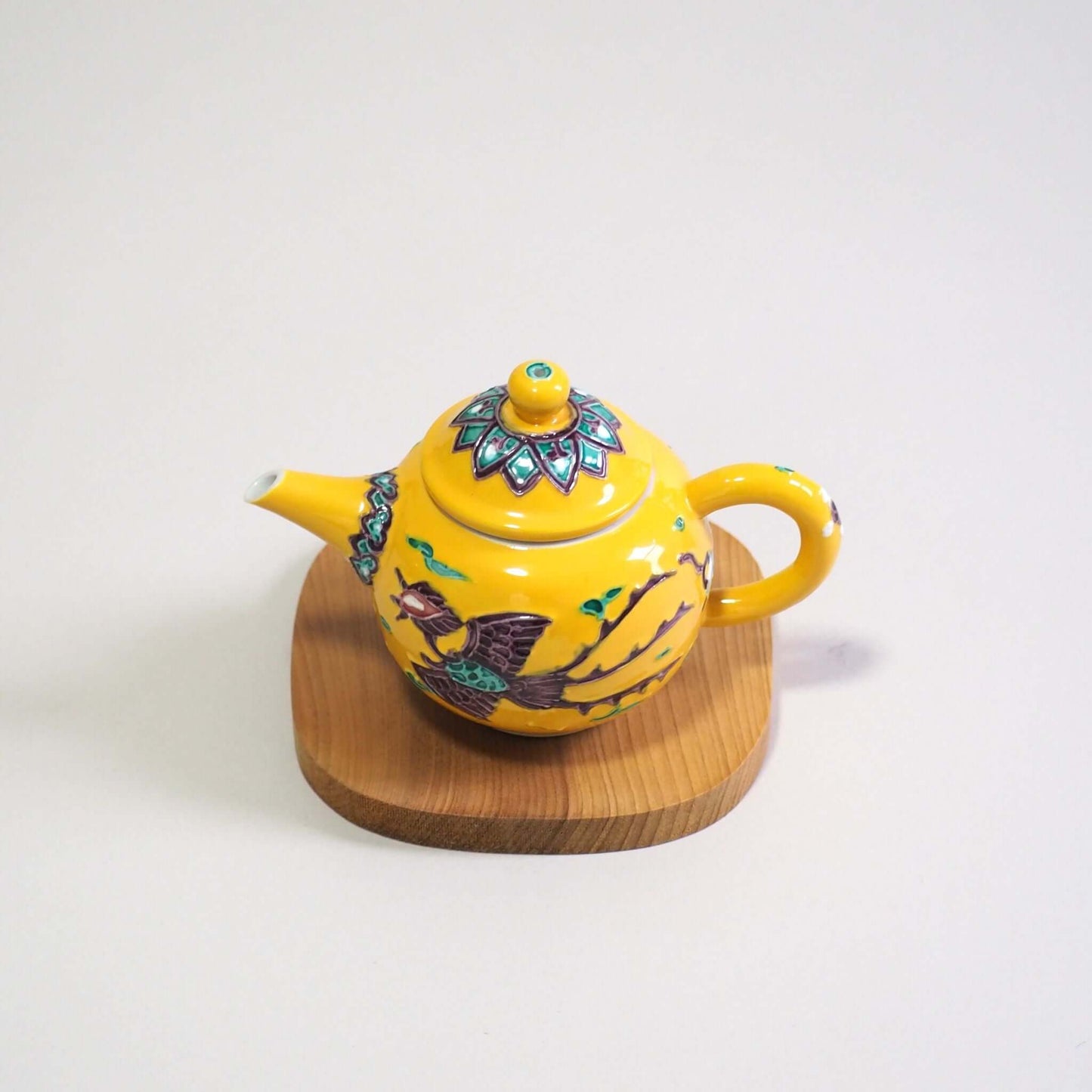 Looking at a Kyo-yaki Shōami yellow-glazed phoenix teapot from a slightly elevated angle.