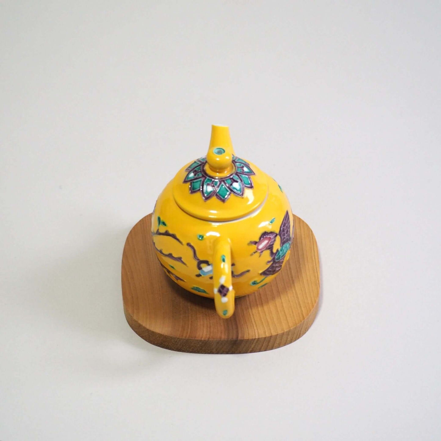 Looking at the back of the Kyo-yaki Shōami yellow-kochi phoenix teapot from a diagonal above view.